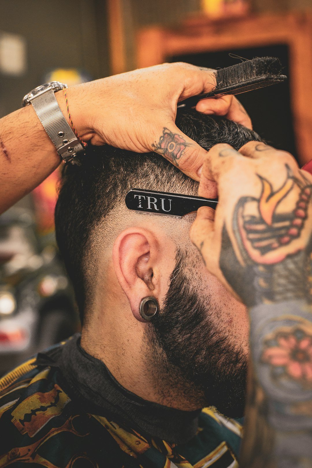 Burst Fade: The Ultimate Guide to 10 Styles, Who It Suits and How to Ask Your Barber 2 Barber shaping a burst fade around the ear with a razor