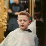 Young boy getting one of the cool boys haircuts at a barbershop
