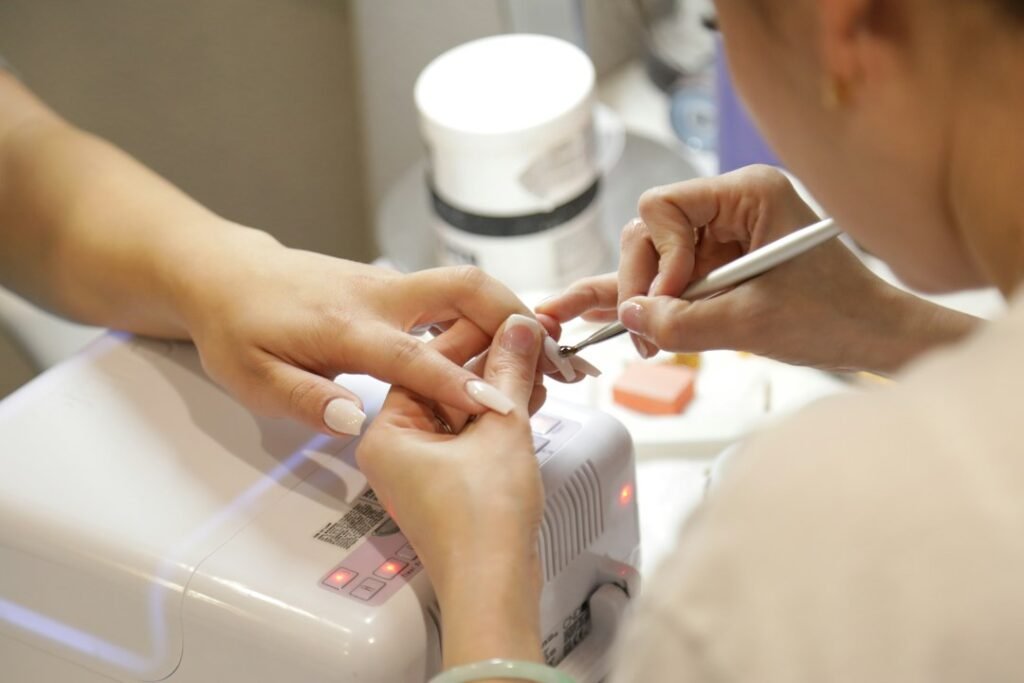 Nail technician filing nail shapes at a salon