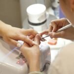 Nail technician filing nail shapes at a salon