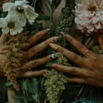 Hands with spring nails holding white daisies