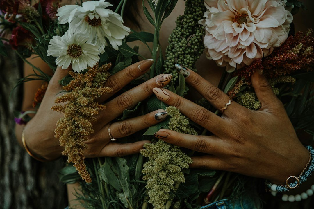 Hands with spring nails holding white daisies